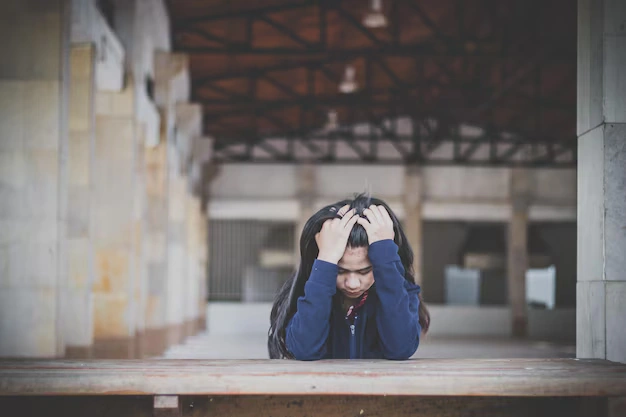 A person holding their head in frustration, symbolising stress and emotional struggle.